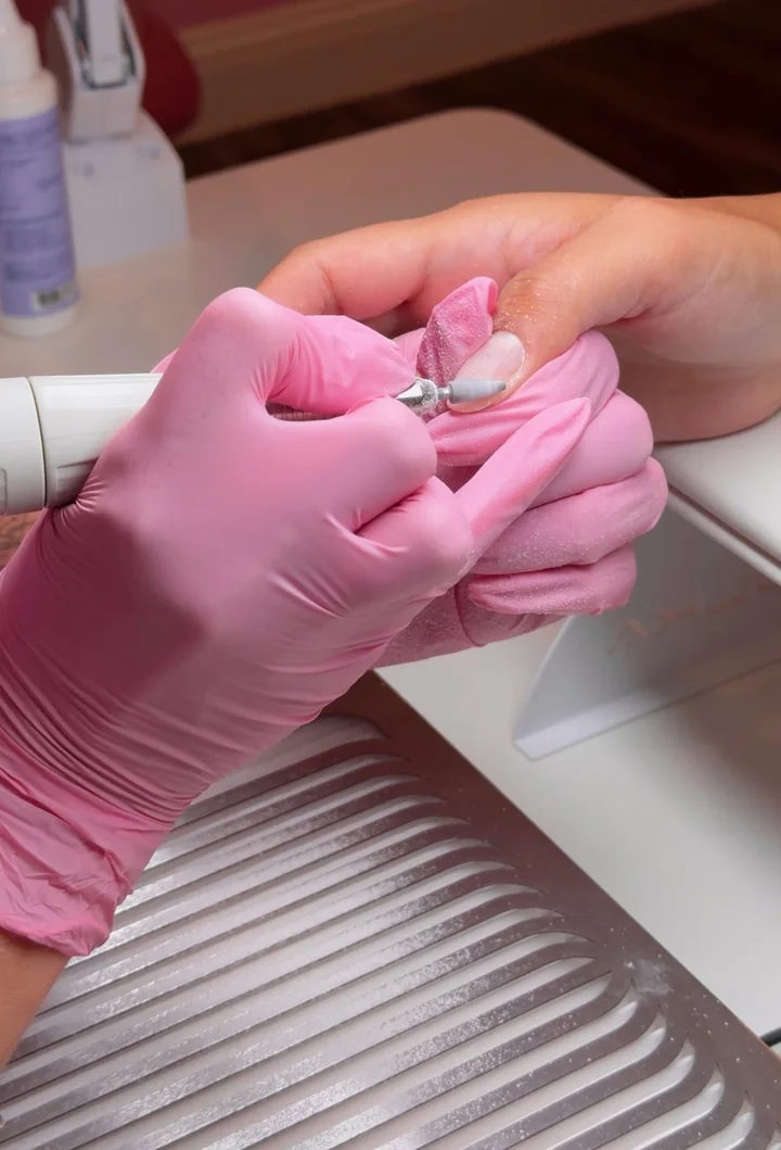 Detailed gel nail work at YA Studio with an e-file and pink gloves