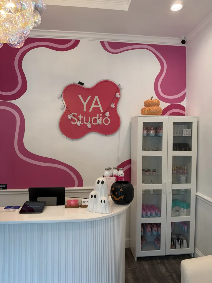 YA Studio reception with pink wall design and the YA Studio sign